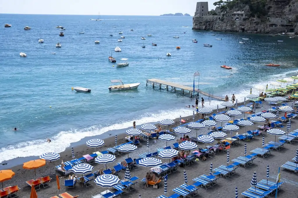 a view of the ocean and blue beach umbrellas in the shore