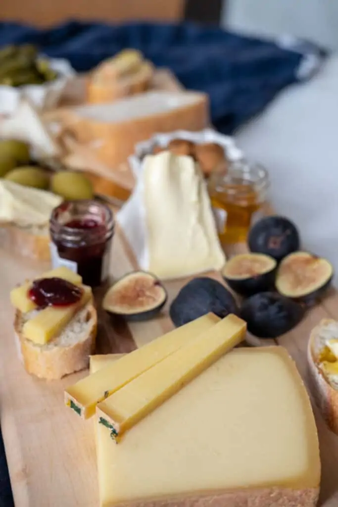 sliced cheeses on cheeseboard with figs