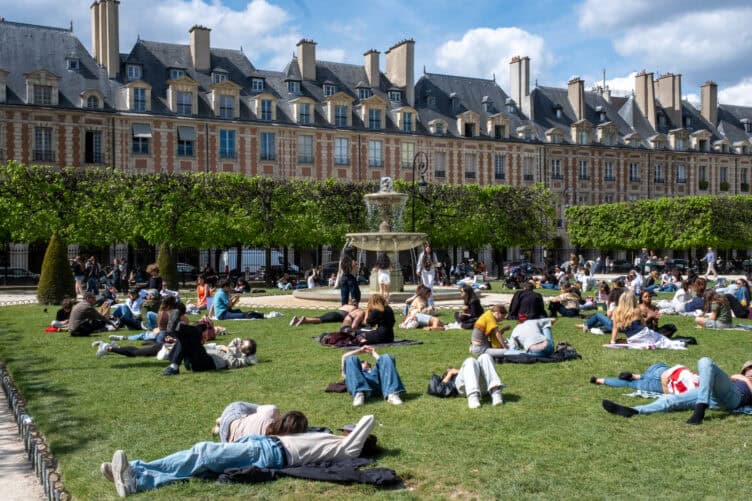 Parisians in Place des Vosges for picnic season spring sunny weather 