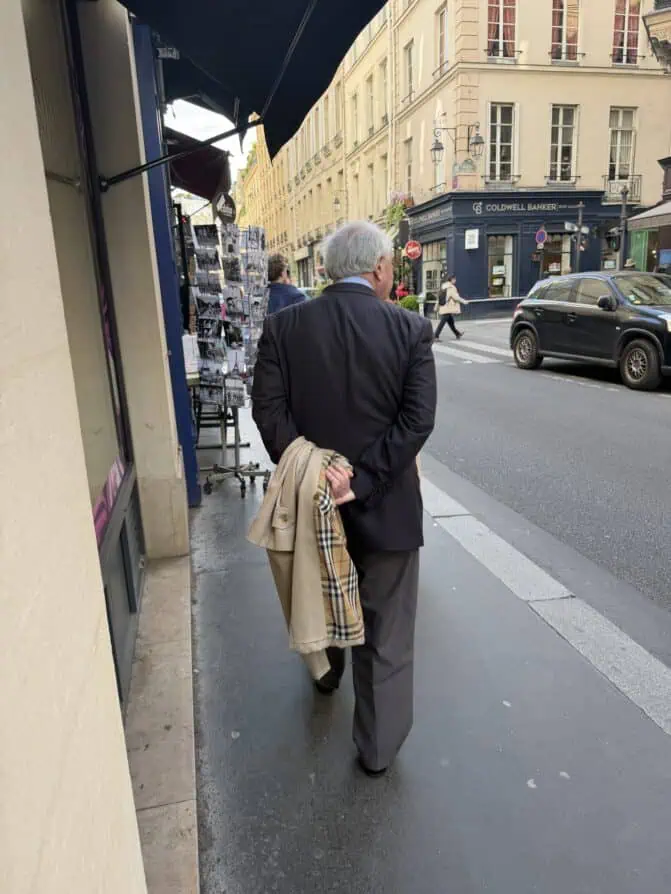 parisian with trench coat behind his back