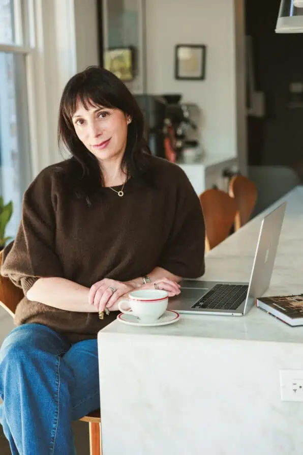 Rebecca Plotnick brown sweater blogging at home with laptop